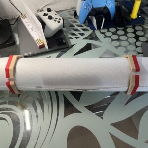 Zwei rot-beige Leinwandklemmen halten eine aufgerollte Diamond-Painting-Leinwand zusammen